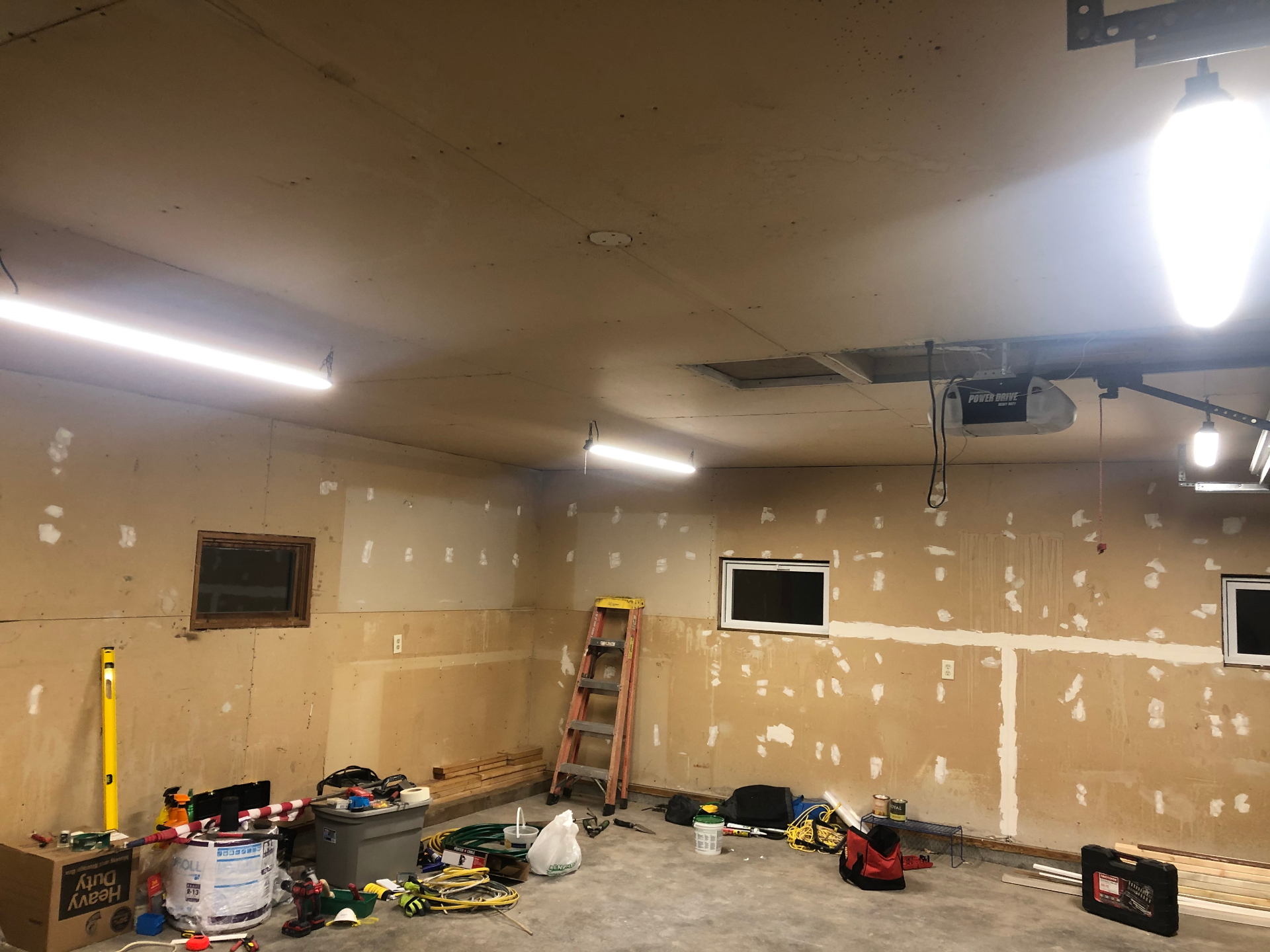 Garage interior mid-repair with patched drywall walls and a repaired ceiling section