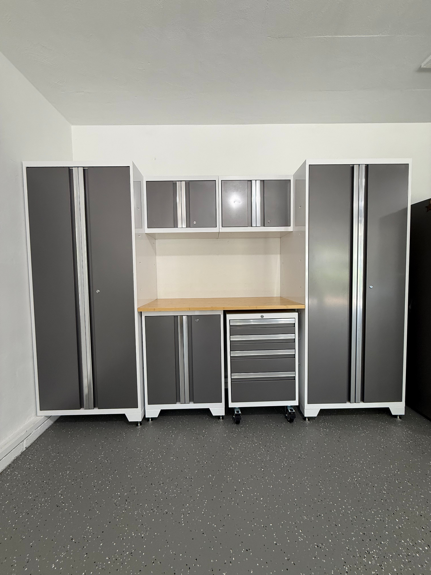 Installed gray and white modular garage cabinet system with butcher-block workbench