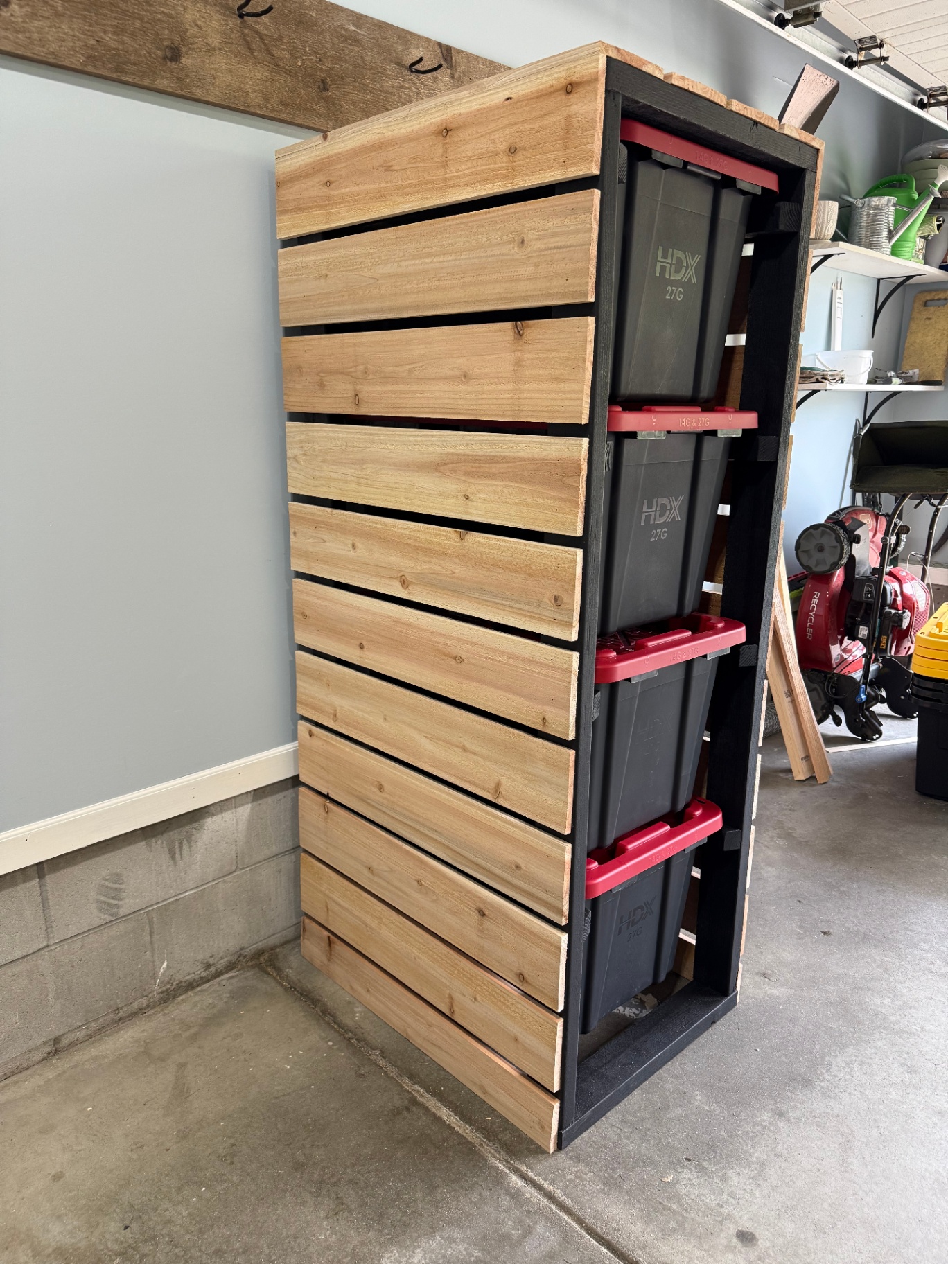 Side view of a custom tote storage rack showing horizontal cedar slat cladding over a black wood frame