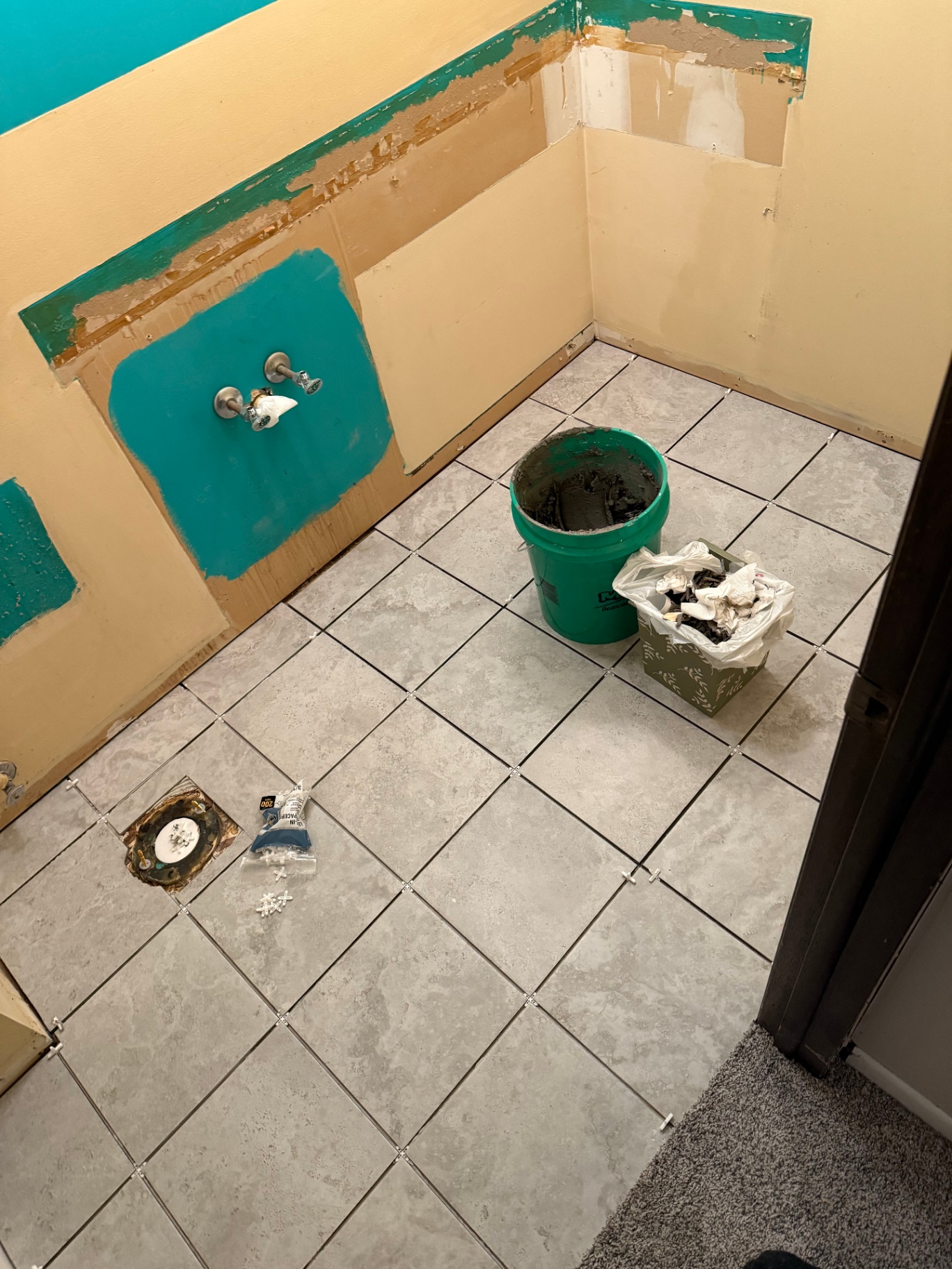 Grey stone-look bathroom floor tile freshly set with plastic spacers still in place