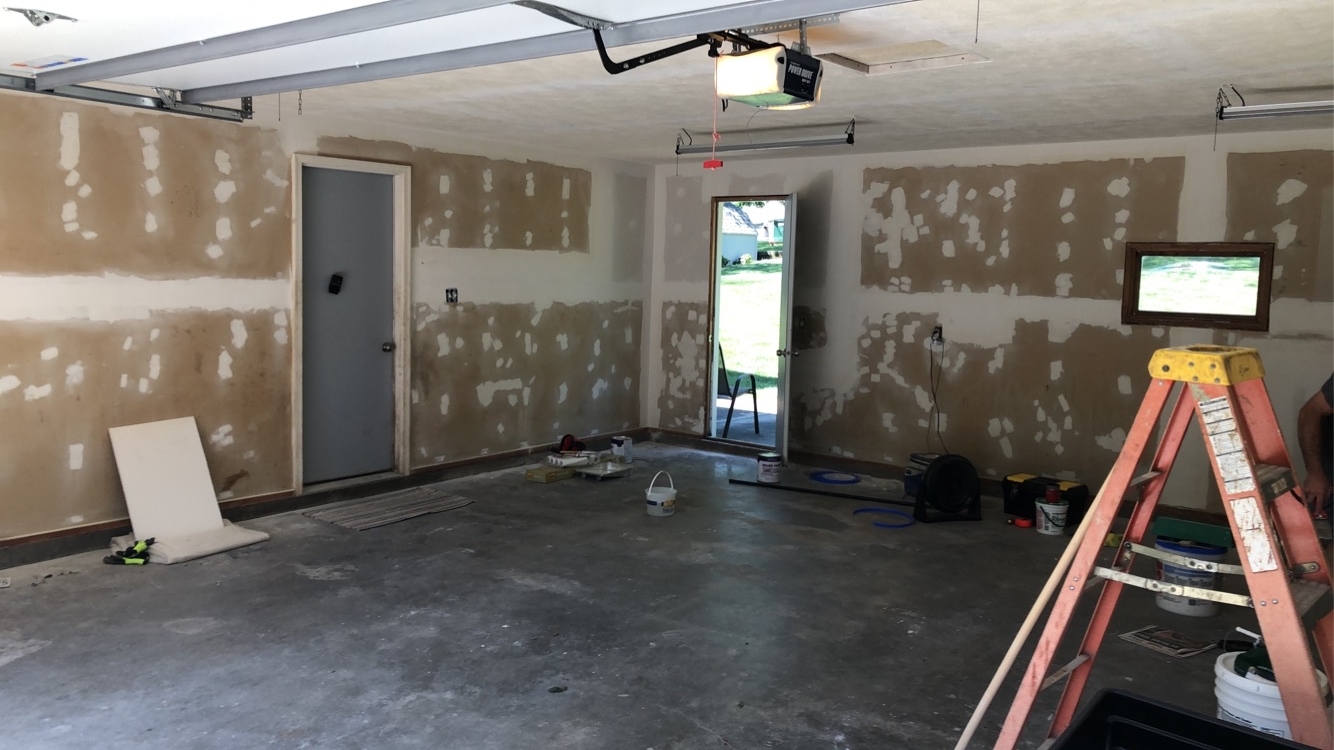 Garage interior with drywall walls covered in fresh joint compound patches, prepped for primer and paint