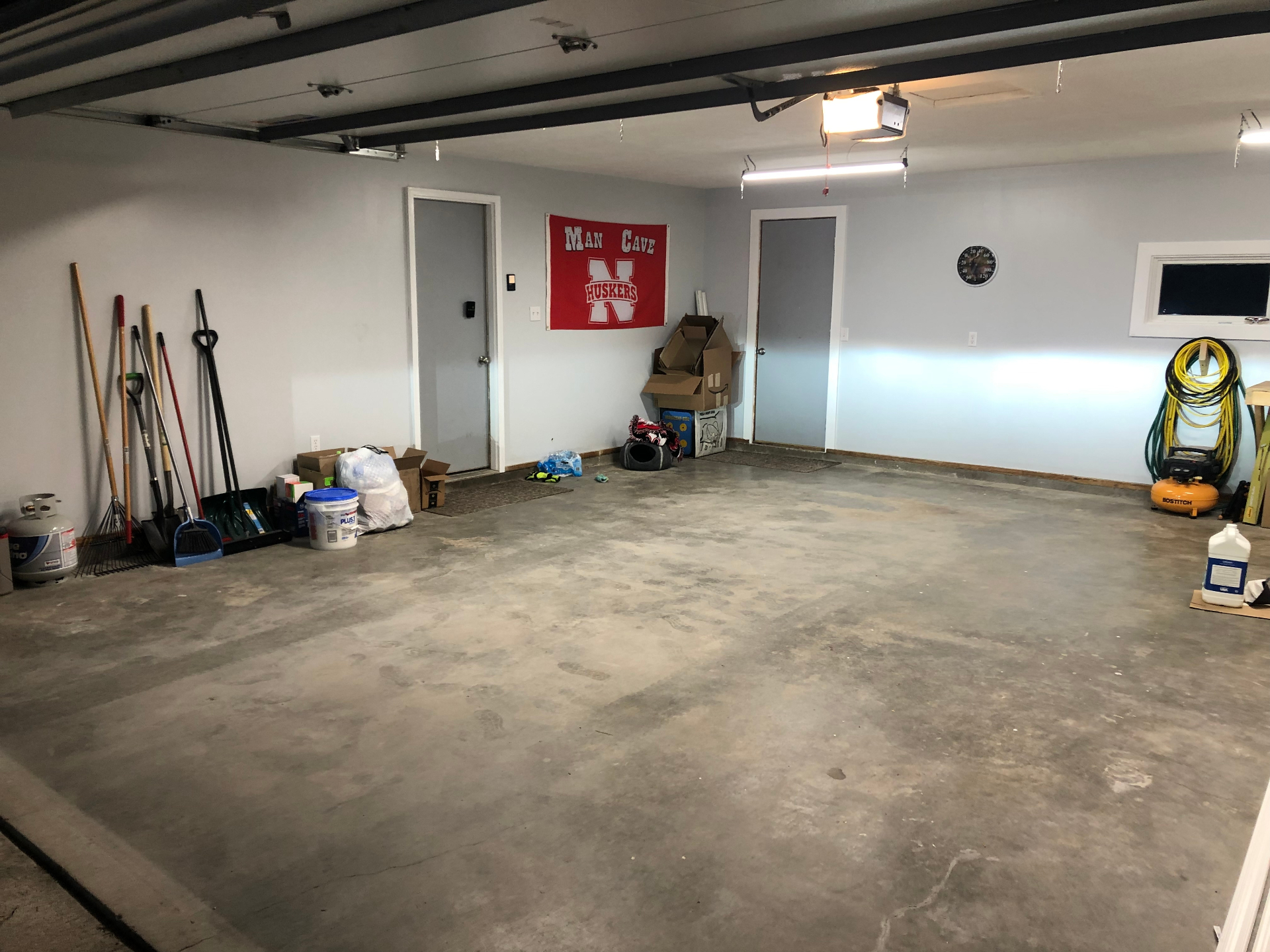 Clean, empty two-car garage with tools lined up along one wall after a cleanout