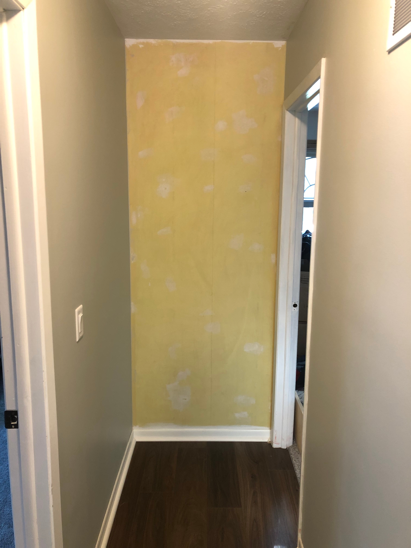 Narrow hallway end wall in original yellow paint with visible patch spots