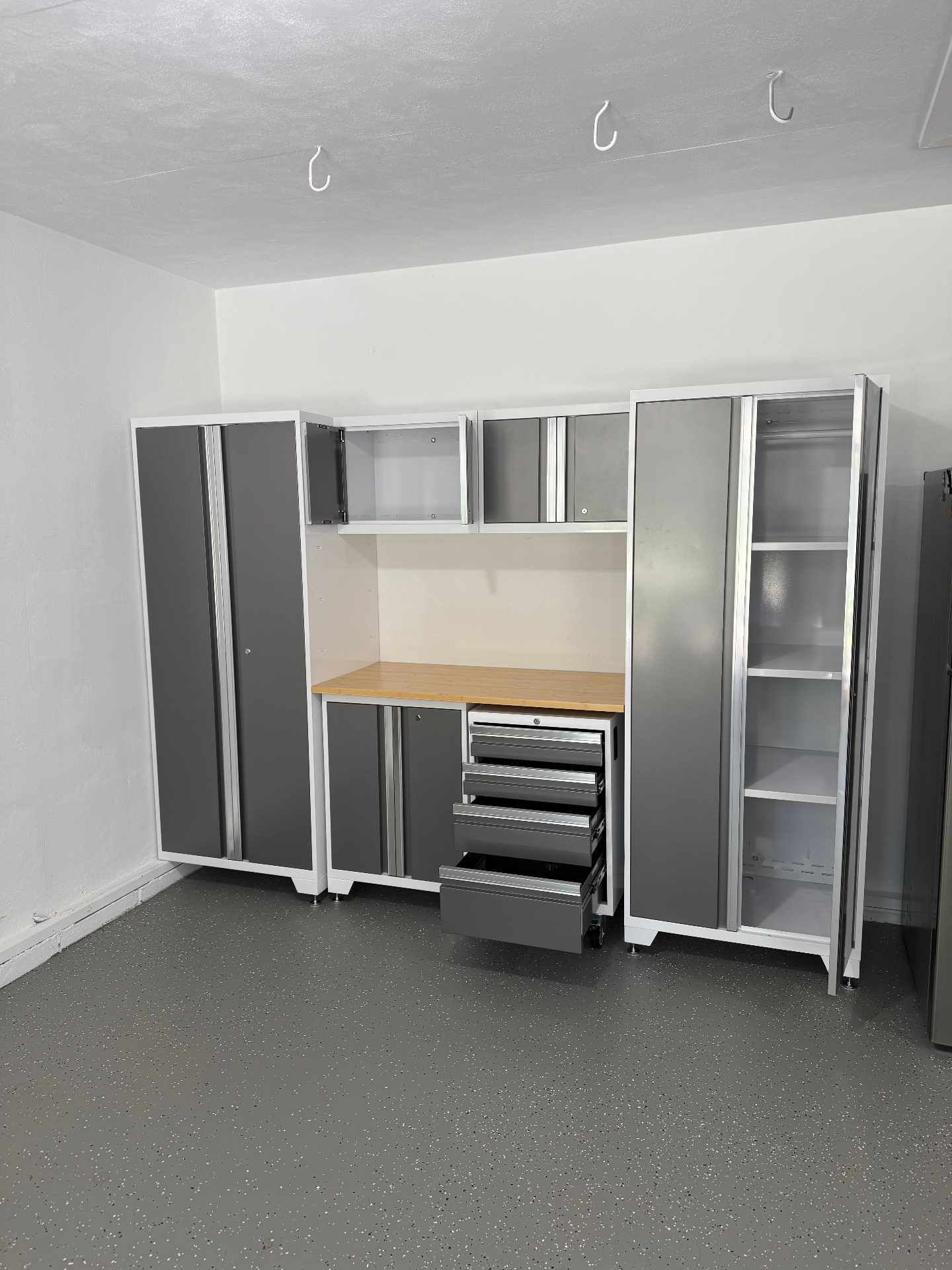 Detail of installed garage cabinet system with one lower drawer pulled open and upper cabinet doors ajar