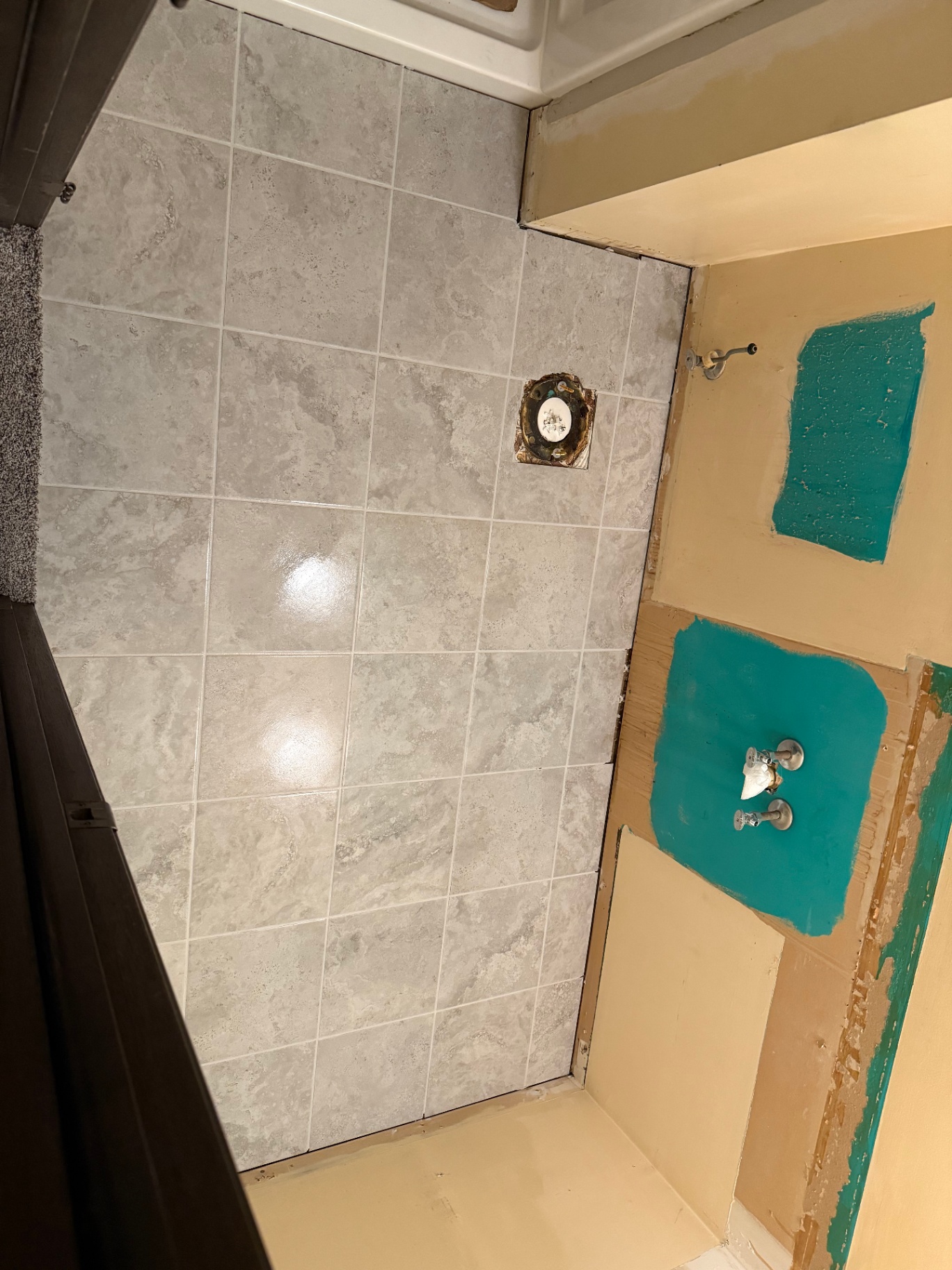 Fresh grey stone-look tile laid on a bathroom wall and floor during installation